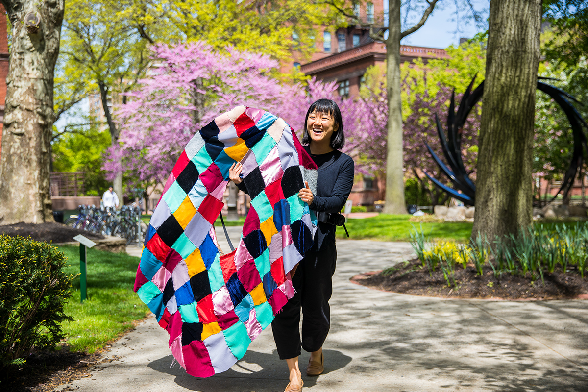 Student holding a colorful fabric art piece outside