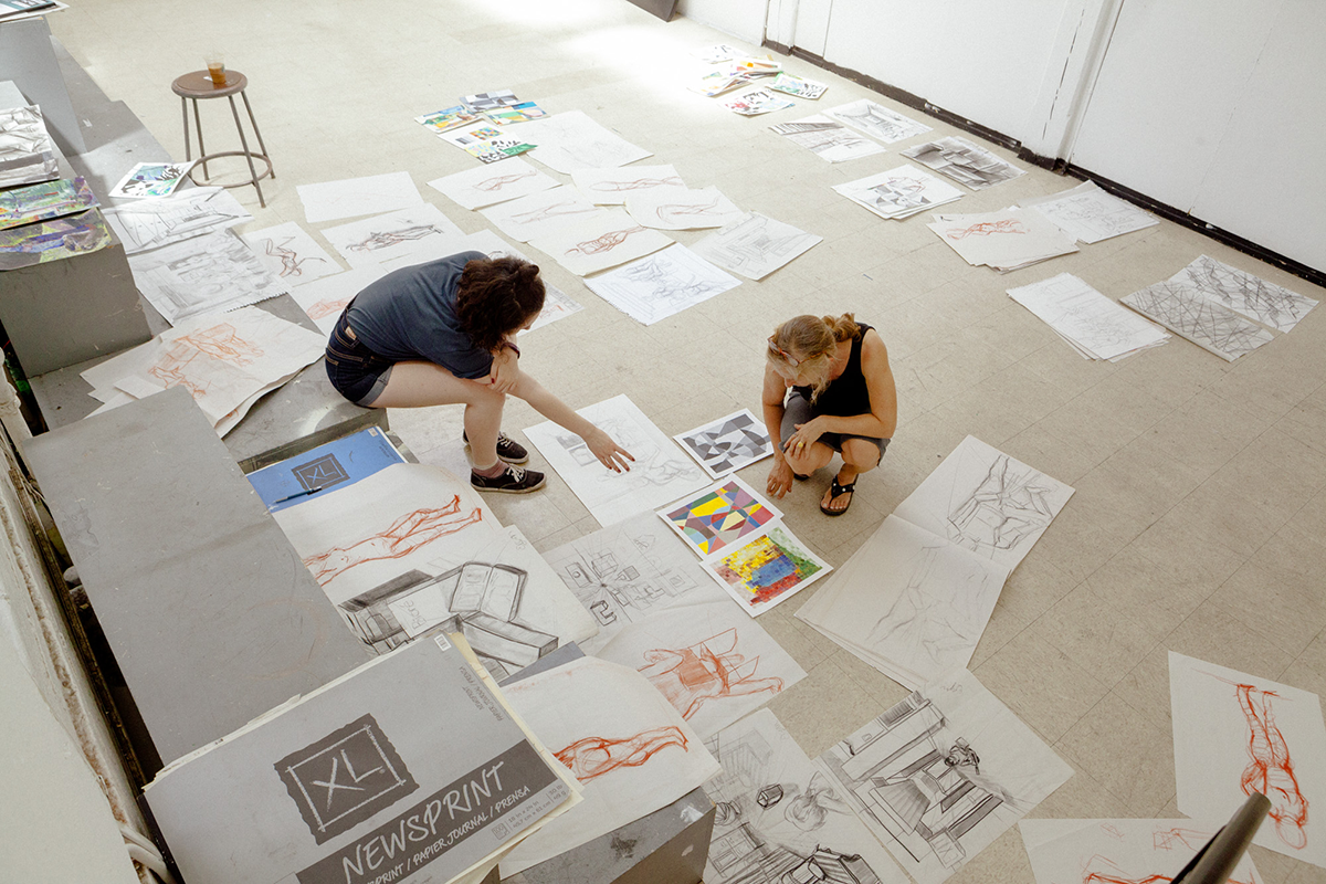 Two students looking at drawings spread on the floor