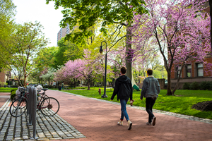 Two students walking through the outside of the campus in spring