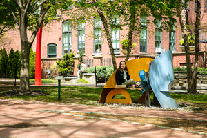 Two students sitting outside on sculpture like benches smiling